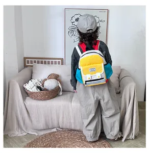 Rear view of a child wearing a colorful patchwork backpack in a cozy indoor setting