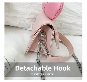 Detail of pink leather mini bag showing the detachable metal hook and D-ring side design