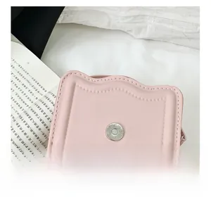 Detail view of pink mini square bag with scalloped edges and magnetic snap closure