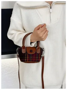 Dettaglio della mini borsa in lana scozzese con manici e tracolla in pelle marrone