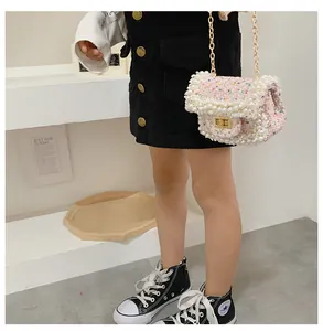 Close-up of pink tweed child handbag with pearl trim and gold chain worn by a girl