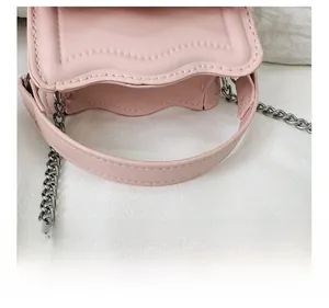 Detail of pink mini bag with scalloped edge, silver chain strap and stitched handle