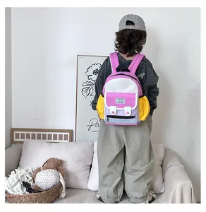 Rear view of child wearing colorful patchwork backpack in a modern minimalist room