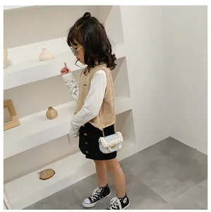 Detail shot of a light blue quilted crossbody bag with pearl strap on a child fashion model