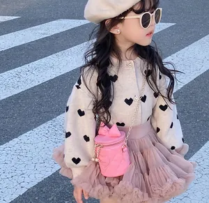 Detail of pink quilted crossbody bag with bow and pearl button knit cardigan for girls