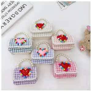 Dettaglio di borse in tweed per bambina con manici in perle e ciondoli a cuore colorati