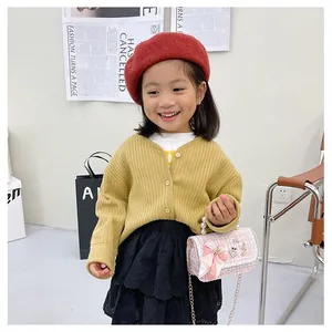 Girl wearing pink plaid handbag with pearl handle and yellow knit cardigan