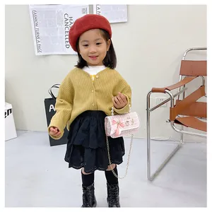Pink tweed bag with pearl handle and bow shown as part of a stylish kids fashion outfit