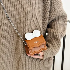 Girl's mini brown crossbody bag with white bow, wave trim and silver chain strap