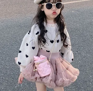 Detail of pink heart-shaped crossbody bag with gold chain strap on a child outfit
