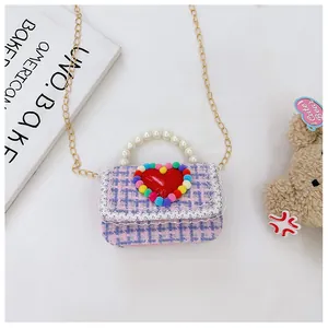Dettaglio borsa a tracolla in tweed rosa per bambina con manico di perle e pompon