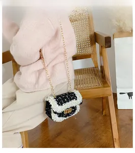Detail of child wearing a black tweed mini crossbody bag with pearl trim and gold chain