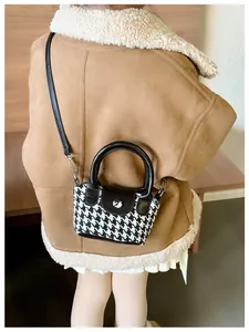 Dettaglio di un bambino con una borsa mini tote vintage pied-de-poule su un cappotto marrone