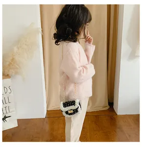 Close-up of black tweed kids crossbody bag with white pearl trim and gold metal lock