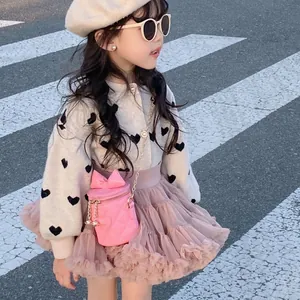 Girl in pink quilted bucket bag and knit cardigan walking on street during daytime