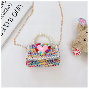 Dettaglio borsa a tracolla in tweed con manico di perle e cuore rosa decorativo