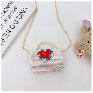 Dettaglio borsa a tracolla bimba in tweed con manico di perle e decoro a cuore