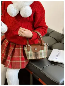 Dettaglio di una bambina con borsa mini in tweed a quadri con manico in pelle e fibbia