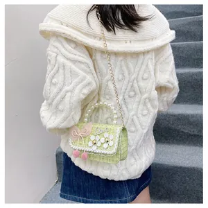 Detail of girls' green tweed crossbody bag with pearl handle and floral embellishments
