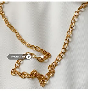 Detailed close-up of the polished golden hardware chain strap on a white knit fabric