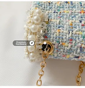 Close-up of light blue tweed fabric texture with pearls and high-quality gold hardware