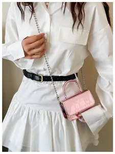 Close-up of a mini pink metallic handbag with crocodile texture and silver ball chain