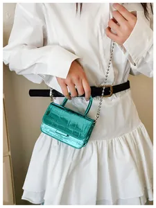 Detailed macro view of metallic green crocodile pattern mini handbag with bead chain strap