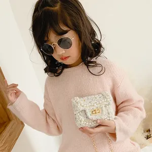 Kids cream tweed crossbody bag with pearl trim and gold chain strap on a small girl