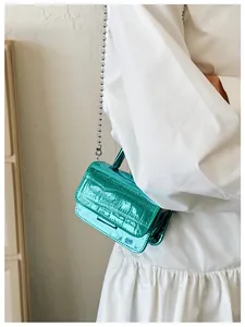 Detail view of metallic green crocodile pattern handbag with silver spherical chain strap