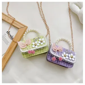 Detail of tweed children's crossbody bags with pearl handles and floral decorations