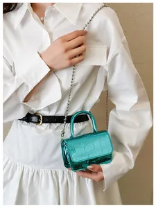 Detail view of mini turquoise crocodile pattern crossbody bag with silver bead chain strap