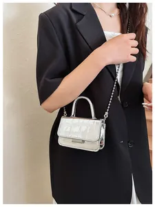 Detail of silver crocodile pattern mini handbag with bead chain strap worn by a model
