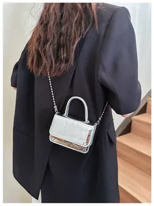 Close-up of metallic silver mini handbag with crocodile texture and metal ball chain