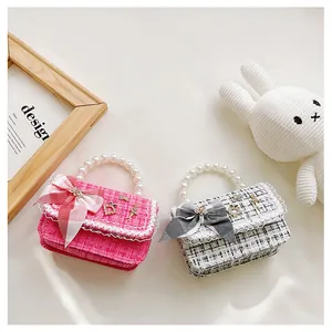 Detail of tweed kids' bags with pearl handles and plaid bows in pink and monochrome