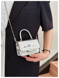 Macro detail of silver mini crossbody bag with crocodile pattern and ball chain strap