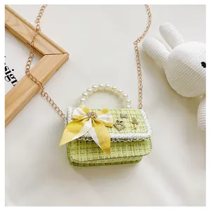 Detail of green tweed kids bag with pearl handle and yellow checkered bow accent