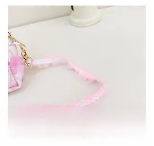 Detail of floral girl crossbody bag with pink lace shoulder strap and golden metal buckle