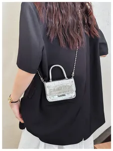 Close-up of metallic silver mini handbag with crocodile texture and silver ball chain