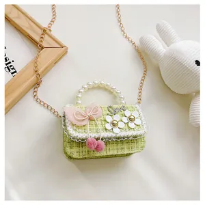 Detail of tweed kids bag with lace trim, pink bow, pearl handle and gold chain strap