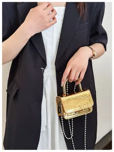 Macro view of gold mini handbag with embossed crocodile texture and metal handle