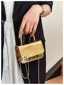 Close-up of golden PU leather mini handbag with crocodile texture and metal chain strap
