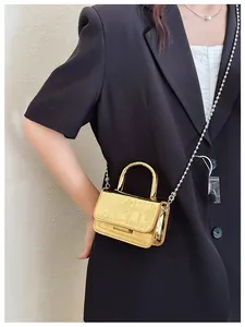 Close-up of golden metallic crocodile-embossed mini handbag with bead chain strap