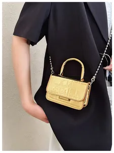 Close-up of golden croc-embossed mini handbag with silver ball chain on black blazer