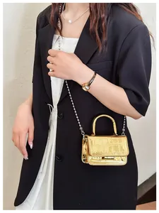 Mini metallic gold crossbody bag with crocodile pattern and pearl chain strap on model