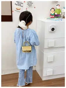 Detail of girls' golden metallic mini handbag with chain strap shown on a model