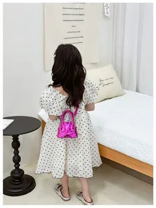 Détail d'un mini sac à bandoulière matelassé rose porté par une petite fille stylée