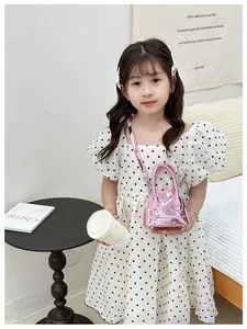 Détail du mini sac rose matelassé avec bandoulière chaîne tenu par une petite fille