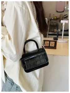 Detail view of black crocodile pattern patent leather mini handbag with silver bead strap