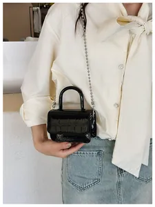 Detail of mini black faux crocodile leather handbag with silver chain strap and top handle