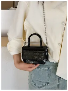 Detail of glossy black faux crocodile leather mini bag with silver ball chain strap